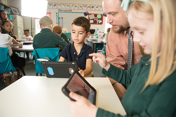 teacher helping students with their iPads